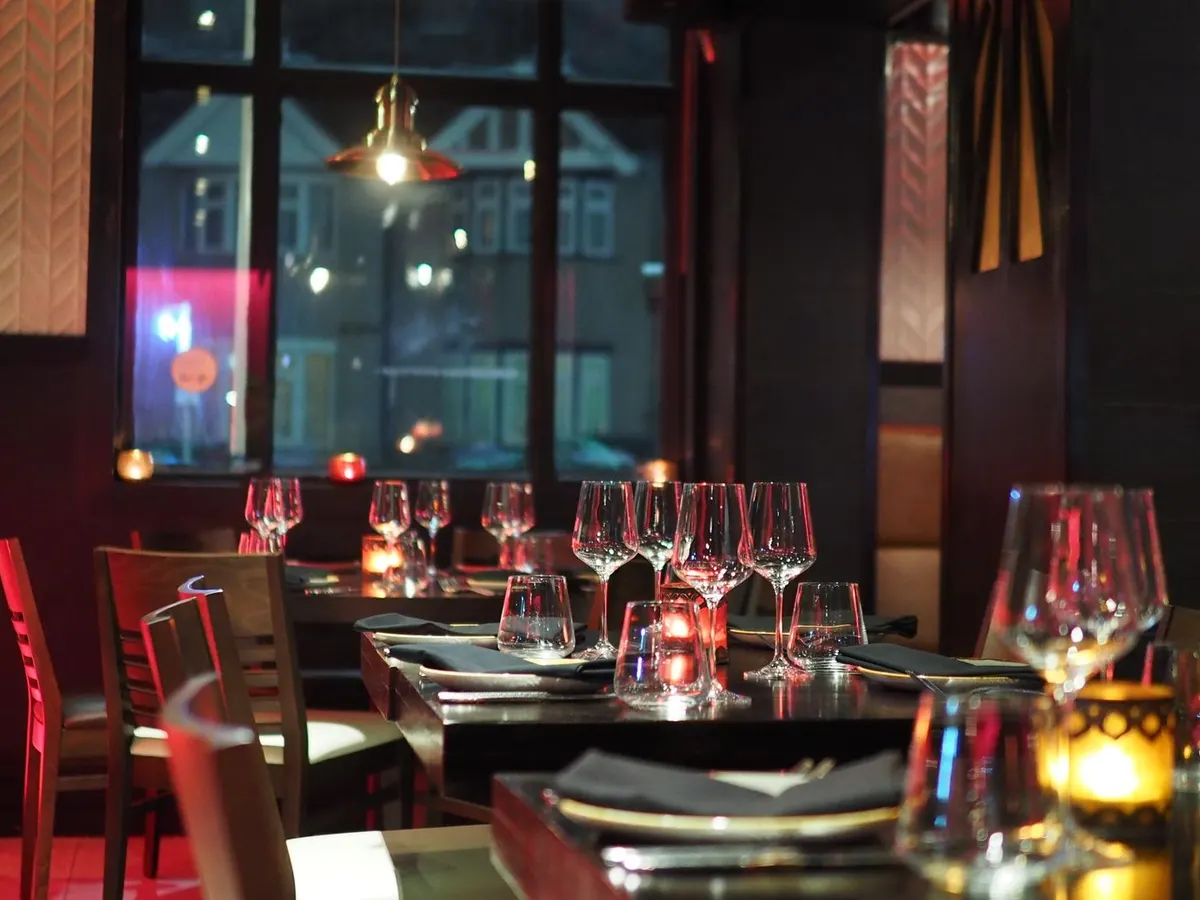 Interior del restaurante iluminado con velas, mesas vestidas para la cena