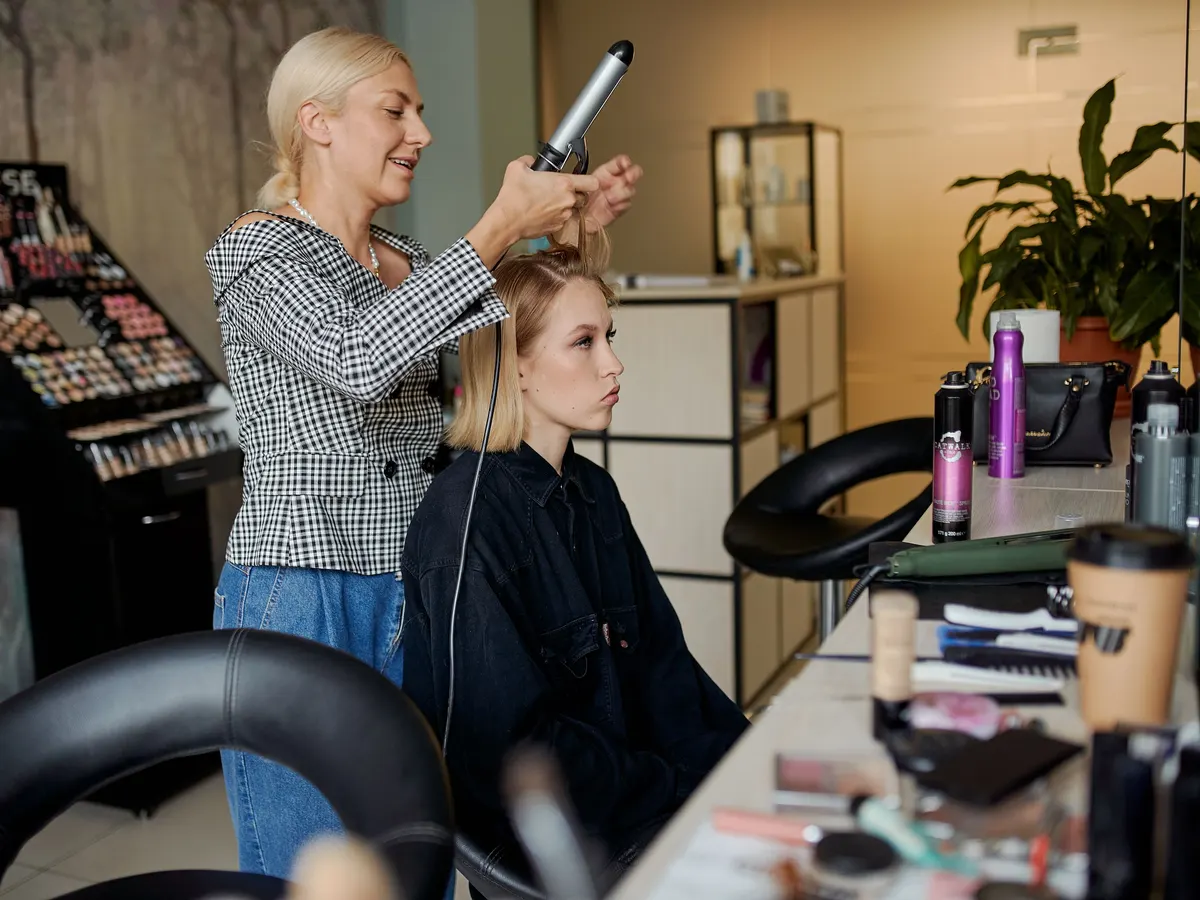 Estilista alaciando el cabello de una clienta con plancha